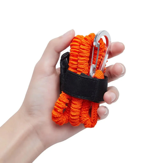 Hand holding an orange paracord keychain with a carabiner on a white background