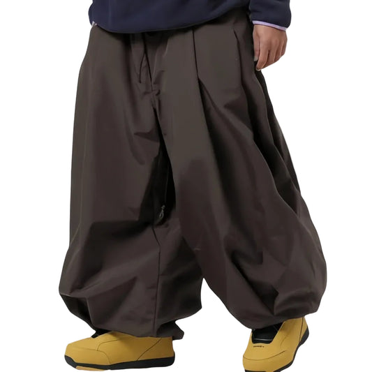 Person wearing brown wide-leg pants and yellow shoes on a light gray background