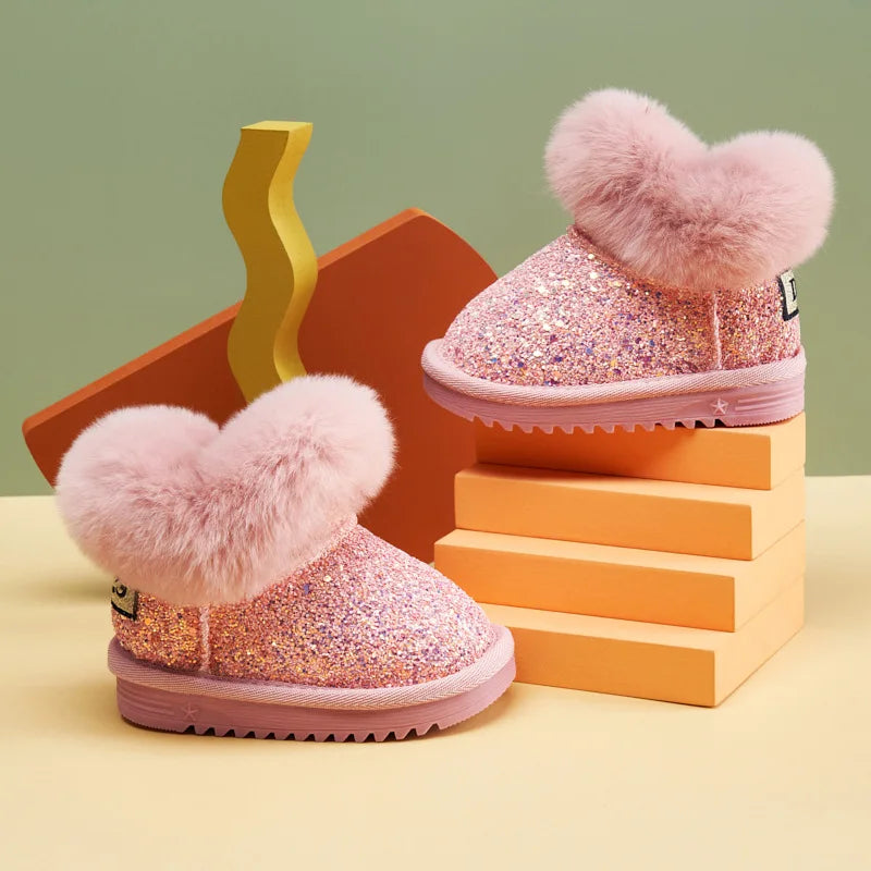 Pink glittery boots with heart-shaped fuzzy toppers on a colorful geometric background