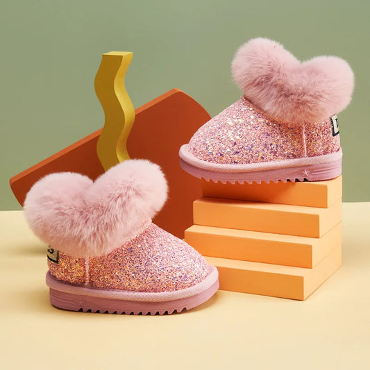 Pink glittery boots with heart-shaped fuzzy toppers on a colorful geometric background