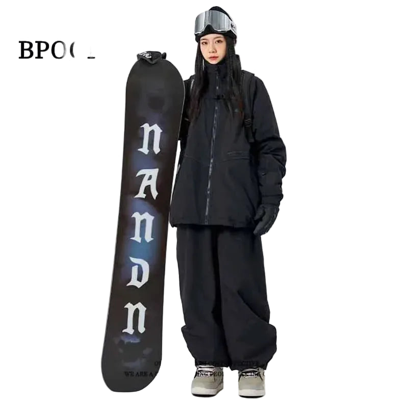 Person in black snowboarding gear holding a black snowboard  on a white background.