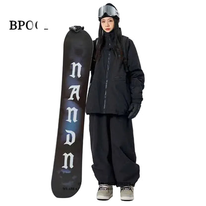Person in black snowboarding gear holding a black snowboard  on a white background.
