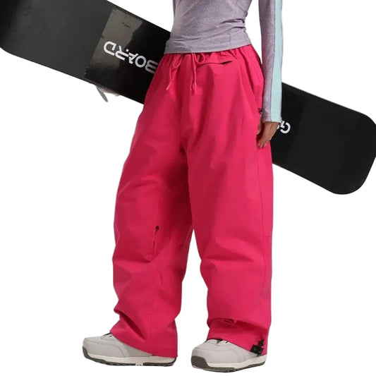 Person wearing bright pink snow pants holding a black snowboard  on a white background