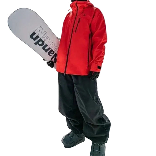 Person in red jacket and black pants holding a snowboard 